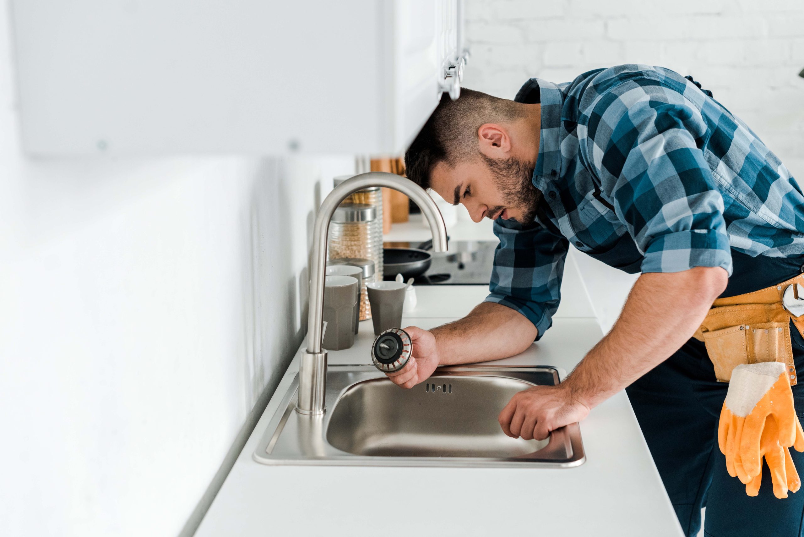 selective focus of handsome bearded repairman working near sink